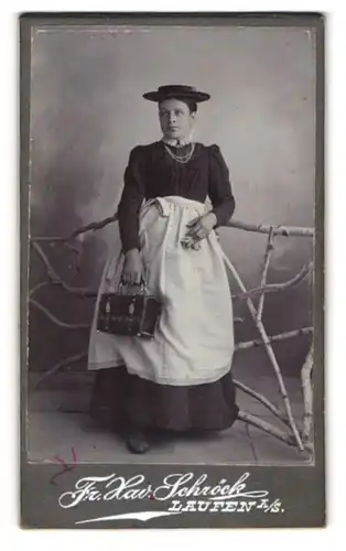 Fotografie Fr. Xav. Schröck, Laufen / Salzach, junge Frau Schlichtner im dunklen Kleid mit Schürze und Handkoffer