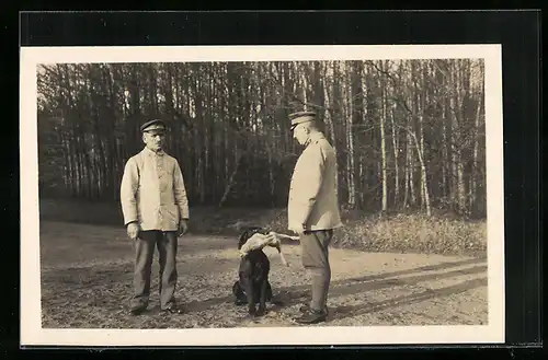 Foto-AK Zwei Soldaten und Jagdhund mit Beute in der Schnauze, Hauptmann Deckert
