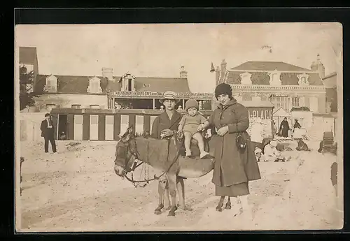 Foto-AK Mutter mit Kleinkind auf dem Rücken eines Esels am Strand