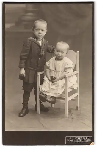 Fotografie J. Fuchs & Co., Charlottenburg, Wilmersdorferstr. 57, Kleiner Junge im Matrosenanzug mit Kleinkind