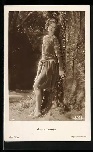 AK Schauspielerin Greta Garbo im samtenen Kleid am Baum lehnend