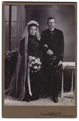 Fotografie Max Hoffmann, Pulsnitz, Ehepaar im schwarzen Brautkleid und im Anzug mit Zylinder