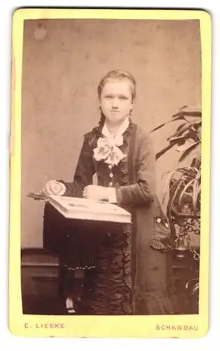 Fotografie E. Lieske, Schandau, junges Mädchen im Kleid mit geflochtenem Zopf samt aufgeschlagenen Fotoalbum