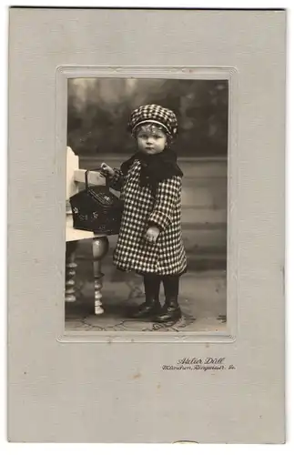 Fotografie Atelier Düll, München, kleines Mädchen im karierten Kleid mit passender Mütze und Picknick Korb