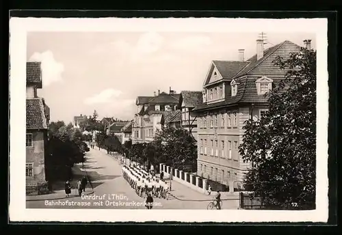 AK Ohrdruf /Th., Bahnhofstrasse mit Ortskrankenkasse, Aufmarsch junger Männer in kurzen Hosen