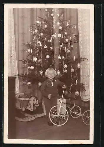 Foto-AK Bube mit Schaukelpferd und Dreirad am Weihnachtsbaum stehend