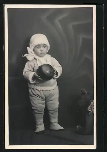 AK Niedliches Kleinkind hält Ball in der Hand, Teddy sitzt auf dem Boden daneben