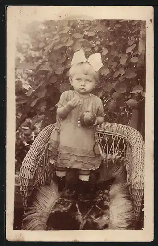 Foto-AK Süsses Mädchen mit Haarschleife hält einen kleinen Ball in der Hand
