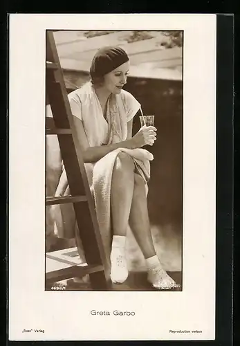 AK Schauspielerin Greta Garbo nachdenklich mit einem Glas Getränk an einer Leiter sitzend