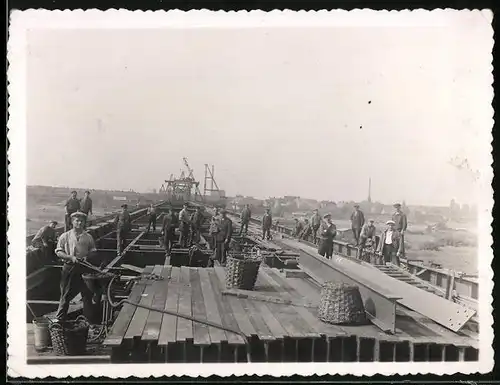 Fotografie Brückenbau, Arbeiter vernieten Metallträger der Brückenkonstruktion