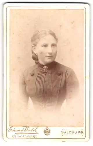 Fotografie Eduard Bertel, Salzburg, Hübsche Dame in schwarzem Kleid und Brosche