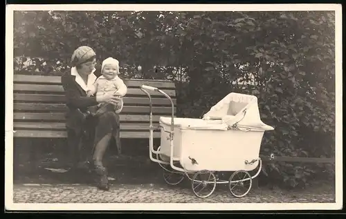 Fotografie Mutter mit Baby im Arm nebst Kinderwagen