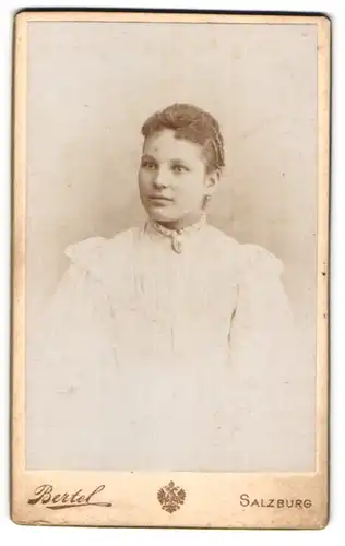 Fotografie Eduard Bertel, Salzburg, Junge Dame in weissem Kleid mit starrem Blick und Brosche