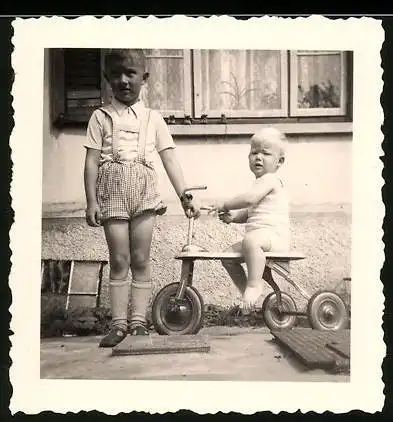 Fotografie Knabe nebst Baby auf Dreirad sitzend