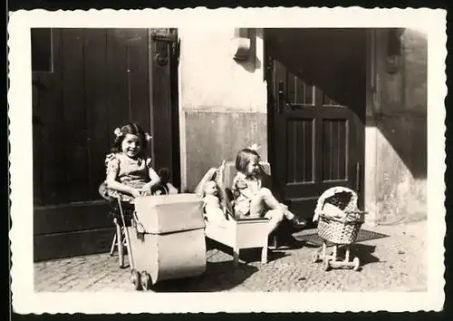 Fotografie Mädchen spielen mit Puppe und Puppenwagen im Hof