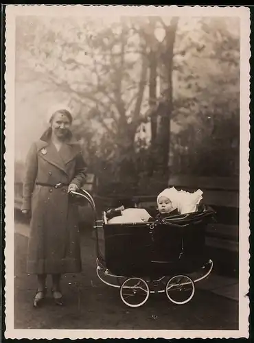 Fotografie glückliche Mutter mit Baby im Kinderwagen beim Spaziergang