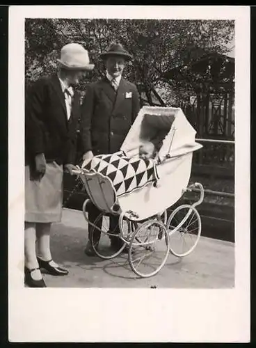 Fotografie glückliche Grosseltern mit Baby im Kinderwagen