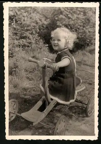 Fotografie Spielzeugm blondes kleines Mädchen auf Draisinen - Tretauto