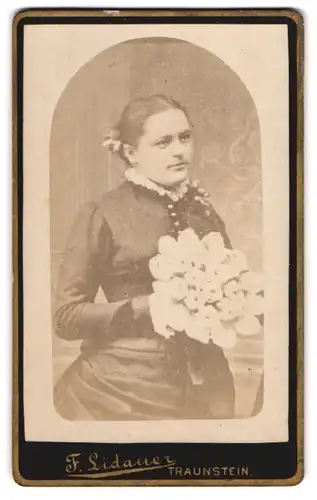 Fotografie F. Lidauer, Traunstein, Junge Frau mit Blumenstrauss im taillierten Kleid