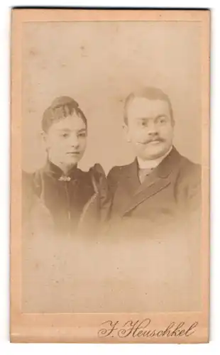 Fotografie J. Heuschkel, Rathenow, Schützen-Str. 6, Herr mit Schnurrbart und junge Dame in schwarzem Kleid mit Dutt