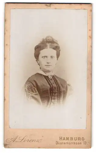 Fotografie A. Lorenz, Hamburg, Düsternstrasse 15, Junge Dame in schwarzem Kleid mit Brosche und Hochsteckfrisur