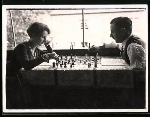 Fotografie Schach - Chess, Paar am Esstisch vor Schachbrett sitzend