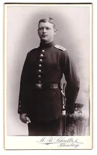 Fotografie M.B. Schultz, Flensburg, Norderhofenden 13, Junger Soldat mit Portepee am Bajonett in Uniform und Schirmmütze