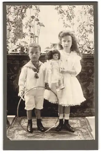 Fotografie unbekannter Fotograf und Ort, Zwei Geschwister mit Spielreif und Puppe