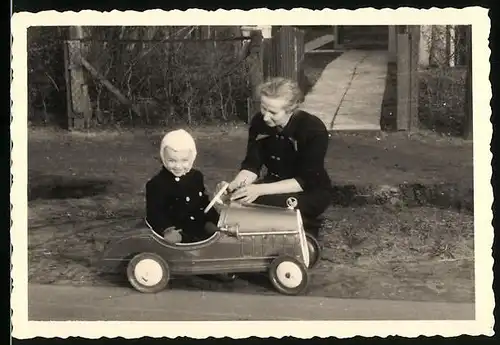 Fotografie glückliches Kind im Tretauto, Spielzeug-Auto sitzend