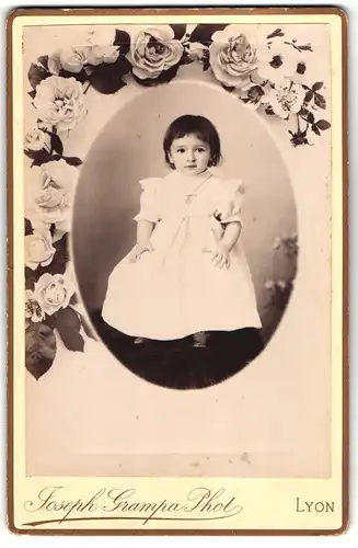 Fotografie Josef Grampa, Lyon, Passepartout-Portrait kleines Mädchen von Blumenblüten umgeben