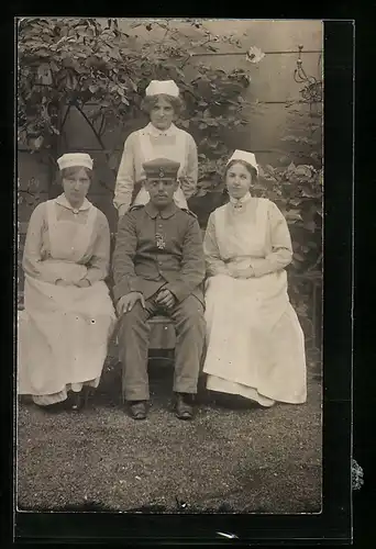 Foto-AK Soldat mit drei Krankenschwestern im Lazaretthof, Rotes Kreuz