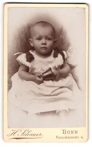 Fotografie H. Schauer, Bonn, Franziskanerstr. 4, Süsses Kleinkind im Kleid mit Glocke