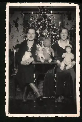 Fotografie Weihnachten, Frauen mit Puppe, Teddybär & Stofftier vor Weihnachtsbaum