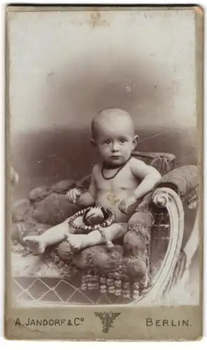 Fotografie A. Jandorf & Co., Berlin, Grosse Frankfurterstr. 113, Nacktes Kleinkind sitzt auf einem Sessel