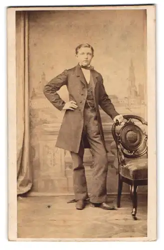 Fotografie F. Wolfram, Dresden, Bursche im Anzug lehnt lässig am Stuhl