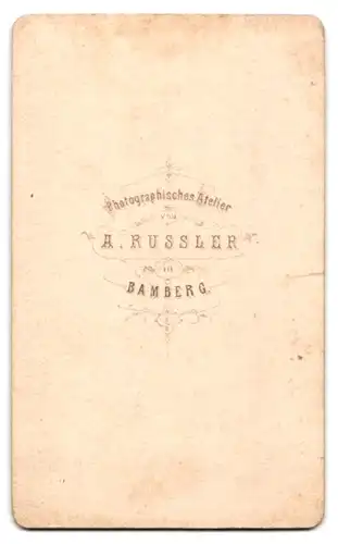 Fotografie A. Russler, Bamberg, Knabe im Anzug an Stuhl lehnend