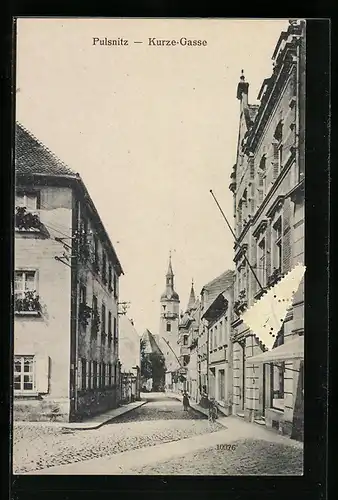 AK Pulsnitz, Kurze Gasse mit Passanten und Kirche