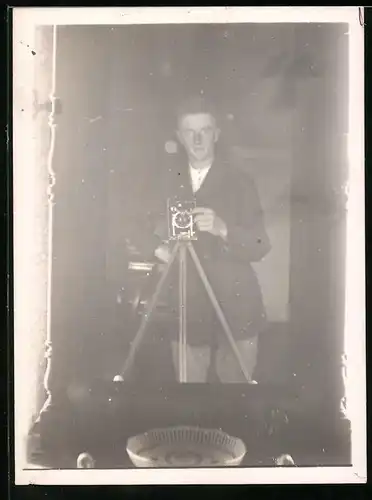 Fotografie Fotograf mit Fotoapparat auf Stativ hat sich vor dem Spiegel abgelichtet