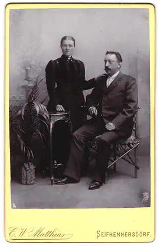 Fotografie E. W. Matthias, Seifhennersdorf, Bürgerliches Paar an einem Tisch