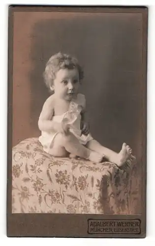 Fotografie Adalbert Werner, München, Portrait niedliches Kleinnkind im Hemdchen auf einem Tisch