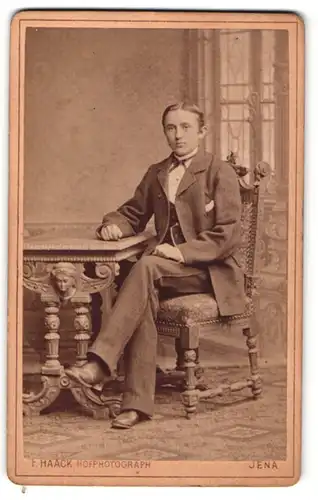 Fotografie Friedrich Haack, Jena, Portrait modisch gekleideter Herr am Tisch sitzend