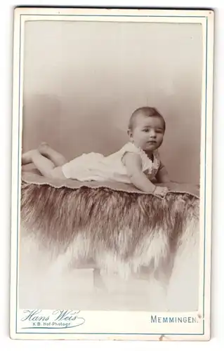 Fotografie Hans Weis, Memmingen, Portrait niedliches Baby im weissen Hemd auf Decke liegend