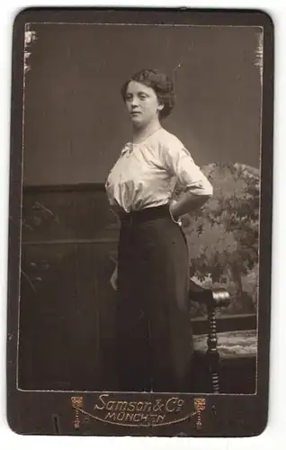 Fotografie Samson & Co., München, Portrait modisch gekleidete Dame vor Sessel stehend