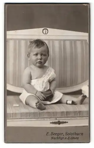Fotografie E. Berger, Solothurn, Portrait Baby im Hemdchen auf einer Bank sitzend