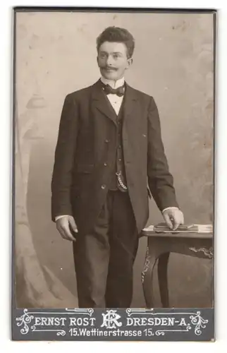 Fotografie Ernst Rost, Dresden-A, Portrait elegant gekleideter Herr an Tisch gelehnt