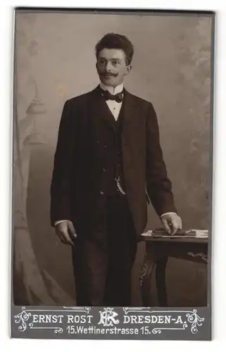 Fotografie Ernst Rost, Dresden-A, Portrait elegant gekleideter Herr an Tisch gelehnt