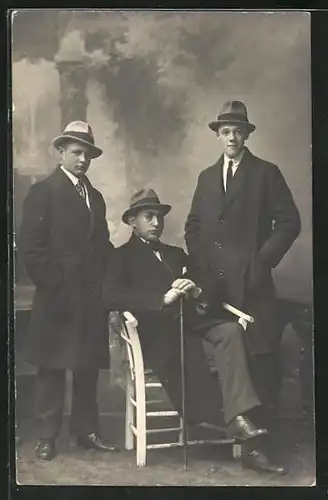 Foto-AK Drei Herren in Mänteln mit Hüten vor einer Studiokulisse