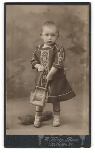 Fotografie O. Kneip, Bonn, Kölnstr. 51, Niedliches Kind mit blonden Haaren in schwarzem Kleid