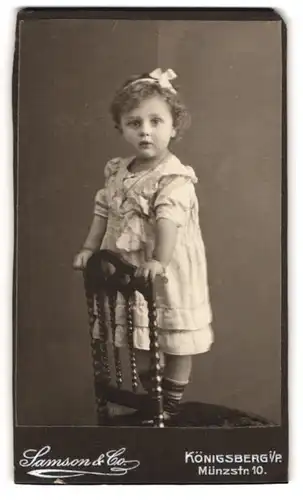 Fotografie Samson & Co., Königsberg i. P., Münzstr. 10, Kleines Mädchen im Kleid steht auf einem Stuhl