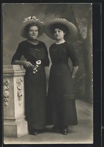 Foto-AK Zwei junge Damen mit Tellerhüten vor Studiokulisse